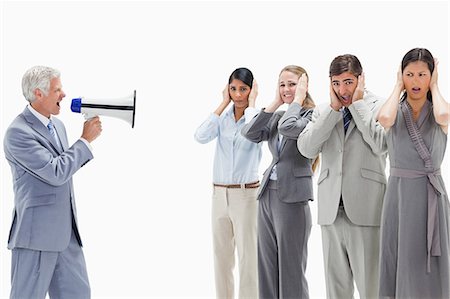 Man yelling in a megaphone at business people with their hands over their ears against white background Stock Photo - Premium Royalty-Free, Code: 6109-06002792