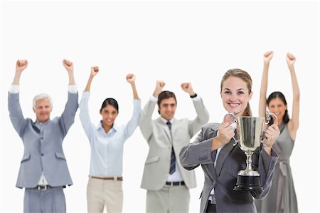 Close-up of a blonde woman holding a cup with enthusiastic business people behind her against white background Stock Photo - Premium Royalty-Free, Code: 6109-06002803