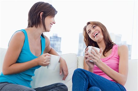 Young woman talking to her friend and laughing while sitting on a sofa Stock Photo - Premium Royalty-Free, Code: 6109-06003299