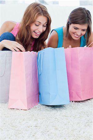 Teenage girls smiling and having a look at shopping bags Stock Photo - Premium Royalty-Free, Code: 6109-06003354