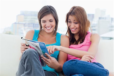 Teenage girl showing an article of a magazine to a friend while pointing it Stock Photo - Premium Royalty-Free, Code: 6109-06003324