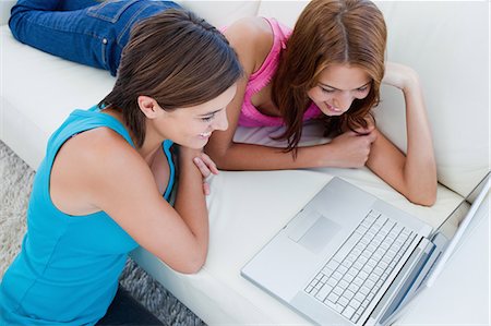 Friend lying on the sofa and her friend sitting on the floor looking at a laptop Stock Photo - Premium Royalty-Free, Code: 6109-06003330