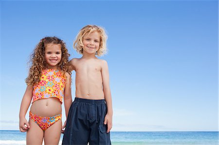 picture of boy and girl in swimsuits - Young siblings standing arm in arm on the beach Stock Photo - Premium Royalty-Free, Code: 6109-06003666