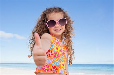 sand sea kids - Smiling girl standing on the beach giving thumb up Stock Photo - Premium Royalty-Free, Code: 6109-06003692