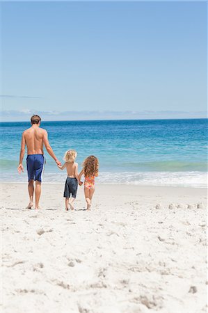 family walking on beach - Young father and his children walking towards the sea Stock Photo - Premium Royalty-Free, Code: 6109-06003755