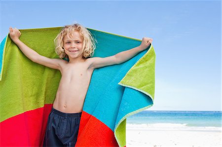 Little boy standing with his towel on the beach Stock Photo - Premium Royalty-Free, Code: 6109-06003707