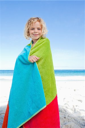 Smiling little boy on the beach wrapped into his towel Stock Photo - Premium Royalty-Free, Code: 6109-06003710