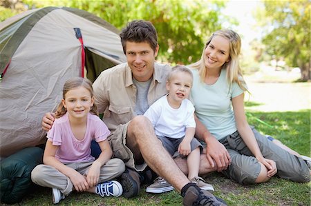 A smiling family together in the park beside their tent Stock Photo - Premium Royalty-Free, Code: 6109-06003866