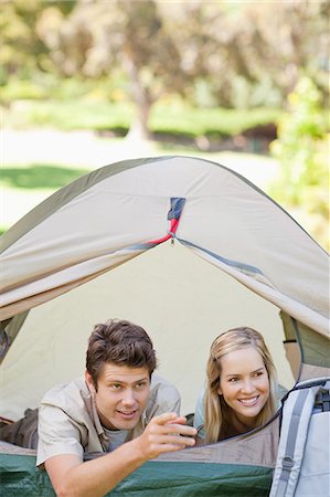 simsearch:6109-06003893,k - A woman being shown something by her boyfriend as they both lie down in the tent together Stock Photo - Premium Royalty-Free, Code: 6109-06003888