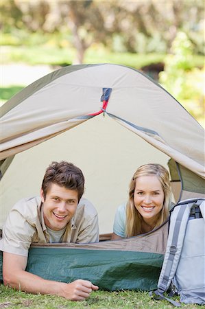 simsearch:6109-06003893,k - A smiling man and woman lie in the bed as the man lets his arm just outside of the tent Stock Photo - Premium Royalty-Free, Code: 6109-06003889