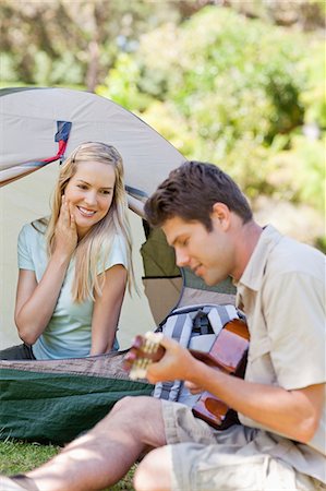 simsearch:6109-06003893,k - A man plays a serenade for his girlfriend as he sits beside the tent she is in Stock Photo - Premium Royalty-Free, Code: 6109-06003901