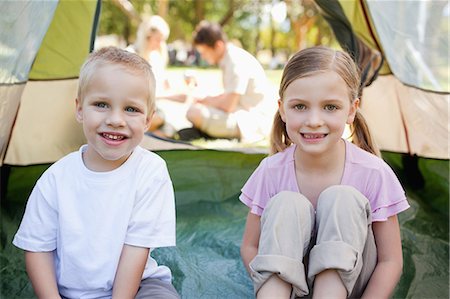 simsearch:6109-06003893,k - A smiling brother and sister sit inside of the tent with their parents outside Stock Photo - Premium Royalty-Free, Code: 6109-06003910
