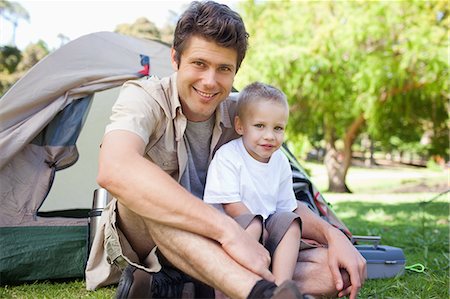 simsearch:6109-06003893,k - A smiling father and son sit together while just outside of the tent Stock Photo - Premium Royalty-Free, Code: 6109-06003916