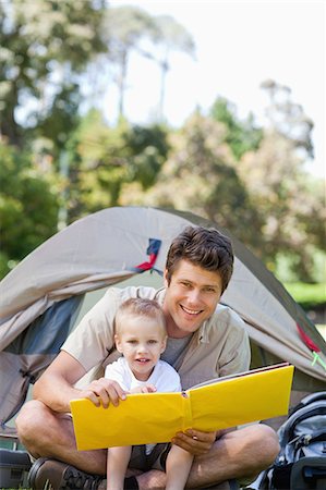 simsearch:6109-06003893,k - A smiling father and son hold a book while looking straight ahead Stock Photo - Premium Royalty-Free, Code: 6109-06003930