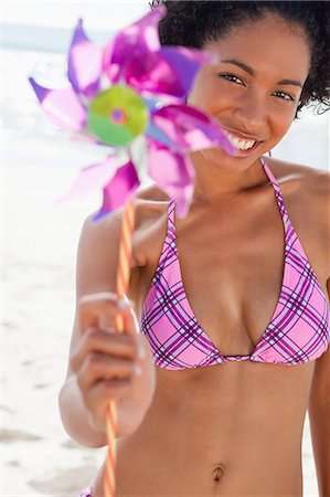 exhaling - Young woman holding a pinwheel while standing upright and showing a great smile Stock Photo - Premium Royalty-Free, Code: 6109-06004144