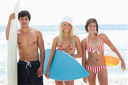 simsearch:6109-06004195,k - Two women and a man standing with surfboards in hand smiling as they are at the beach. Stock Photo - Premium Royalty-Free, Code: 6109-06004200
