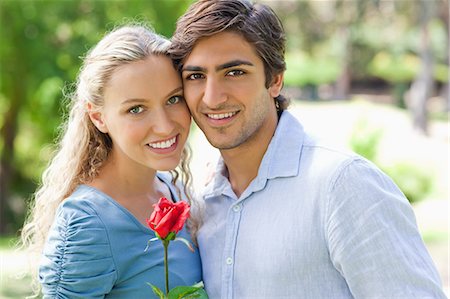 red flowers in the garden - Smiling young couple standing in the park with a rose Stock Photo - Premium Royalty-Free, Code: 6109-06004335