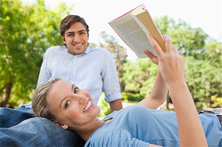 Smiling young woman with her friend in the park reading a book Stock Photo - Premium Royalty-Free, Code: 6109-06004414