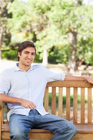 simsearch:6109-06003893,k - Smiling young man sitting on a park bench Stock Photo - Premium Royalty-Free, Code: 6109-06004512
