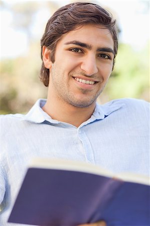 simsearch:6109-06003893,k - Smiling young man with a book in the park Stock Photo - Premium Royalty-Free, Code: 6109-06004515
