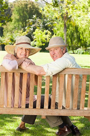 Close-up of a man and a woman embracing each other while sitting on a wooden bench in the park Stock Photo - Premium Royalty-Free, Code: 6109-06004643