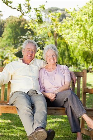 Man smiling while he holds his friend as they sit together on a wooden bench in the park Stock Photo - Premium Royalty-Free, Code: 6109-06004646