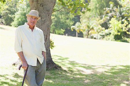 elderly poses - Man standing with a cane while smiling in a park Stock Photo - Premium Royalty-Free, Code: 6109-06004699