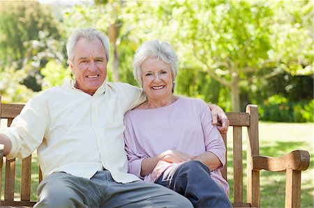 people sitting on bench - Man and a woman smiling happily as they sit on a park bench Stock Photo - Premium Royalty-Free, Code: 6109-06004617