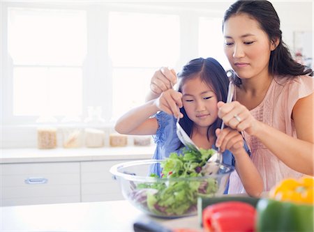 Une fille et sa mère à lancer une salade ensemble dans la cuisine Photographie de stock - Premium Libres de Droits, Code: 6109-06004945