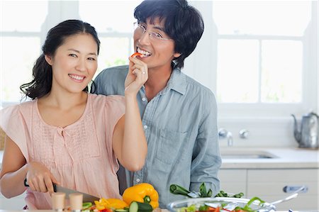 A happy couple chop and eat peppers together while looking straight ahead Stock Photo - Premium Royalty-Free, Code: 6109-06004976