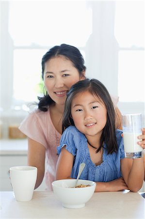 eating together as a family - A daughter about to eat some cereal with her mother standing behind her with a cup in hand Stock Photo - Premium Royalty-Free, Code: 6109-06004999