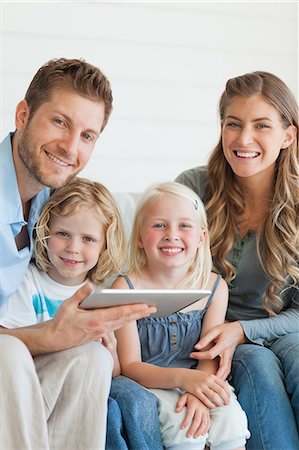 personal computer - A happy family smiling as they sit on the couch look forward with a tablet in the fathers hands Stock Photo - Premium Royalty-Free, Code: 6109-06005053