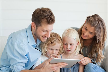 personal computer - The children sit in between their parents watching a tablet pc which is being held by their parents Stock Photo - Premium Royalty-Free, Code: 6109-06005051