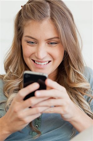 Un plan d'une femme souriante assise et en utilisant son téléphone à texte ami rapproché Photographie de stock - Premium Libres de Droits, Code: 6109-06005032