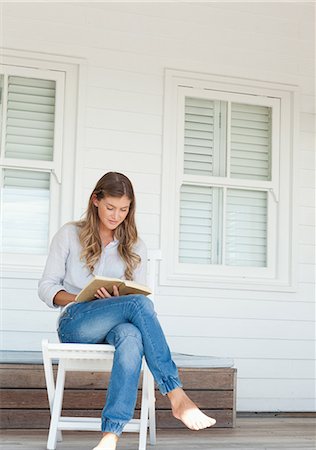 photo of person sitting on porch - A smiling woman sits while reading a book on the porch Stock Photo - Premium Royalty-Free, Code: 6109-06005196