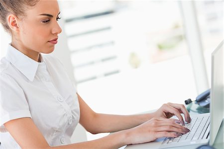 stern - Frizzy haired businesswoman working on a laptop in a bright office Stock Photo - Premium Royalty-Free, Code: 6109-06005351