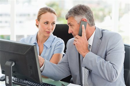 Boss on the phone while an employee is next to him in a bright office Stock Photo - Premium Royalty-Free, Code: 6109-06005322