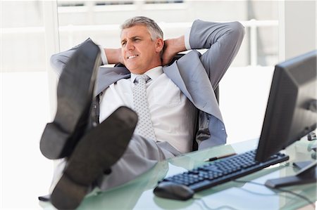 Boss smiling with feet on his desk in a bright office Stock Photo - Premium Royalty-Free, Code: 6109-06005327
