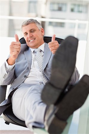 Boss approving with feet on his desk in a bright office Stock Photo - Premium Royalty-Free, Code: 6109-06005330