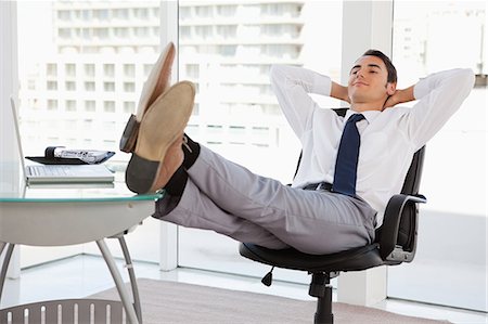 descanso - Happy businessman feet on his desk in a bright office Foto de stock - Royalty Free Premium, Número: 6109-06005563