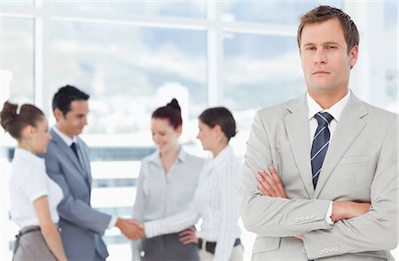 società - Young salesman with arms folded and colleagues behind him Fotografie stock - Premium Royalty-Free, Codice: 6109-06005693