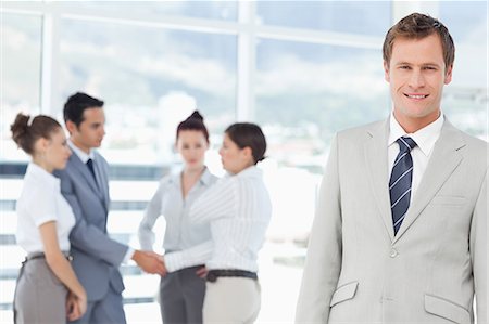 Smiling young salesman with colleagues behind him Stock Photo - Premium Royalty-Free, Code: 6109-06005692