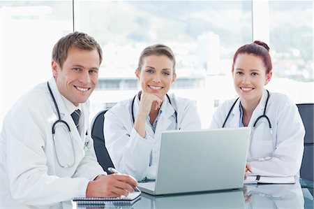 simsearch:6109-06005907,k - Three doctors together with laptop sitting at a table Stock Photo - Premium Royalty-Free, Code: 6109-06005876