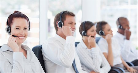 Smiling young call center agent sitting next to her colleagues Stock Photo - Premium Royalty-Free, Code: 6109-06005801