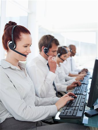 Working young call center employees sitting in a line Stock Photo - Premium Royalty-Free, Code: 6109-06005813