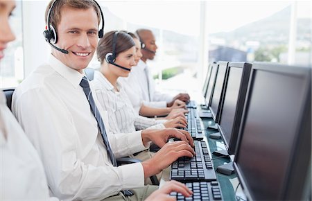 Smiling young call center employee sitting among his colleagues Stock Photo - Premium Royalty-Free, Code: 6109-06005816