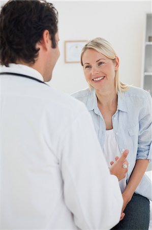 doctor exam room - Woman smiling at her male doctor Stock Photo - Premium Royalty-Free, Code: 6109-06006449