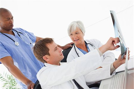 Side view of three doctors talking about an x-ray Stock Photo - Premium Royalty-Free, Code: 6109-06006484