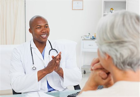 doctor with ethnic patient in office - Smiling doctor talking with his female mature patient Stock Photo - Premium Royalty-Free, Code: 6109-06006662