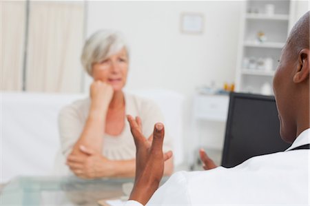 patient and doctor consultation desk - Rear view of male doctor talking to his mature patient Stock Photo - Premium Royalty-Free, Code: 6109-06006674